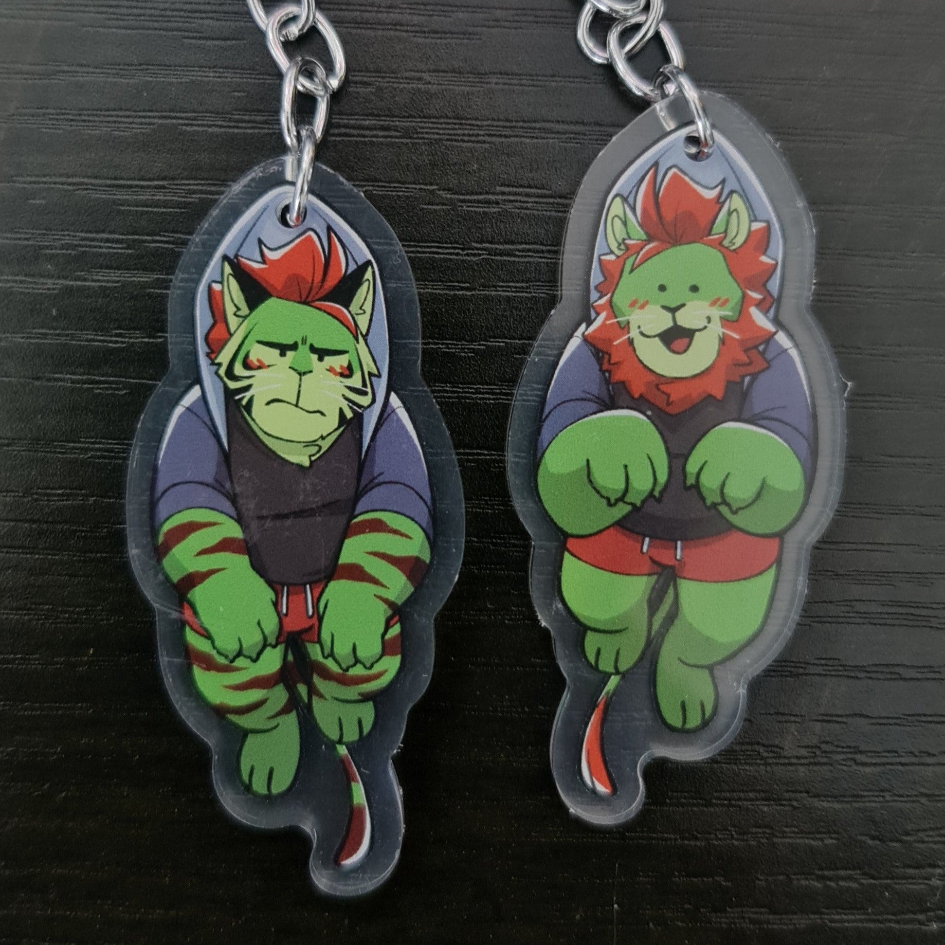 Two keychains, showing the two sides of the Lion/Tiger charm